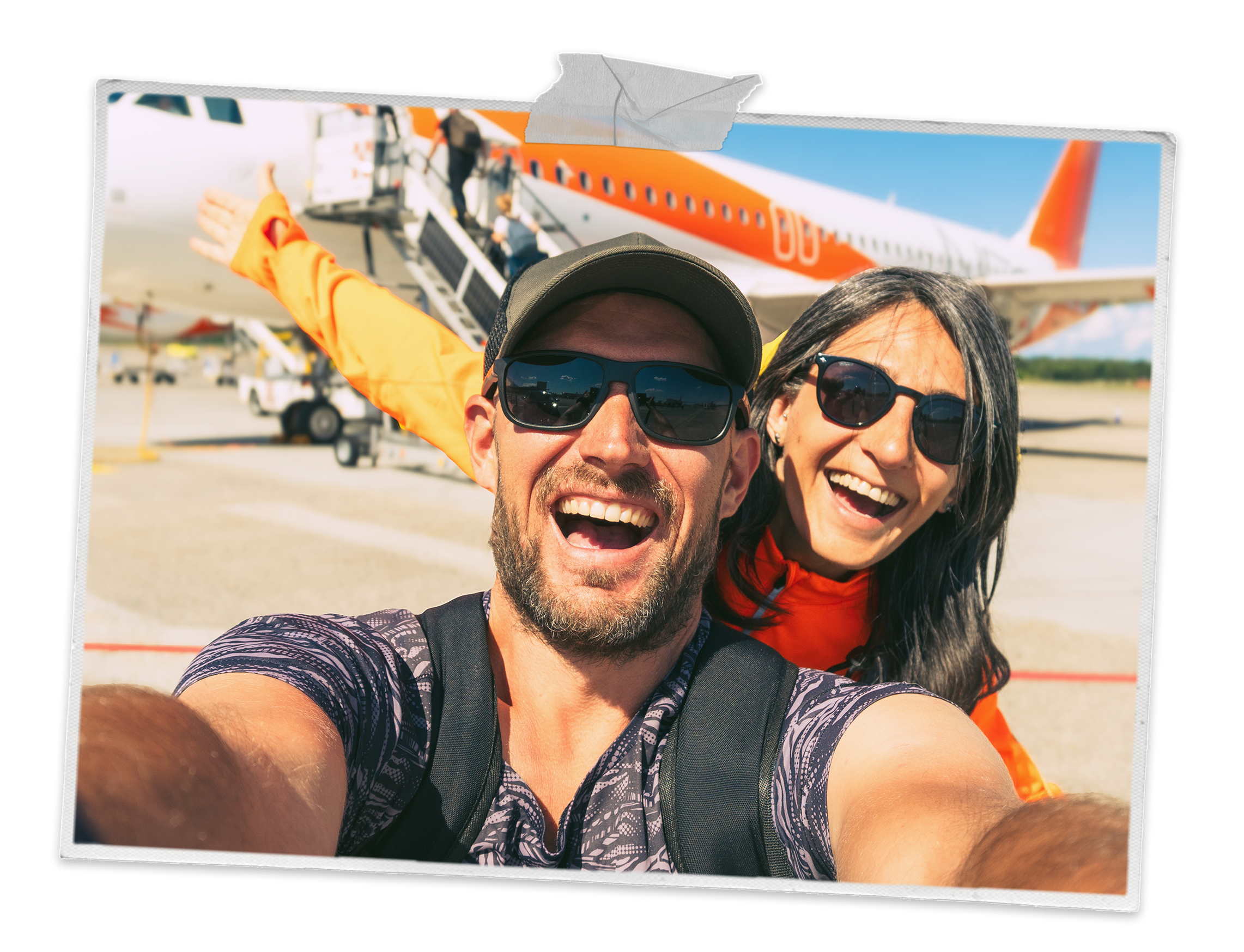 A couple smiling into the camera with a aeroplane behind them