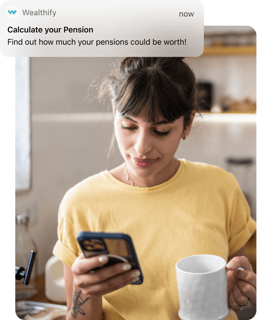 A woman looks at her phone while holding mug