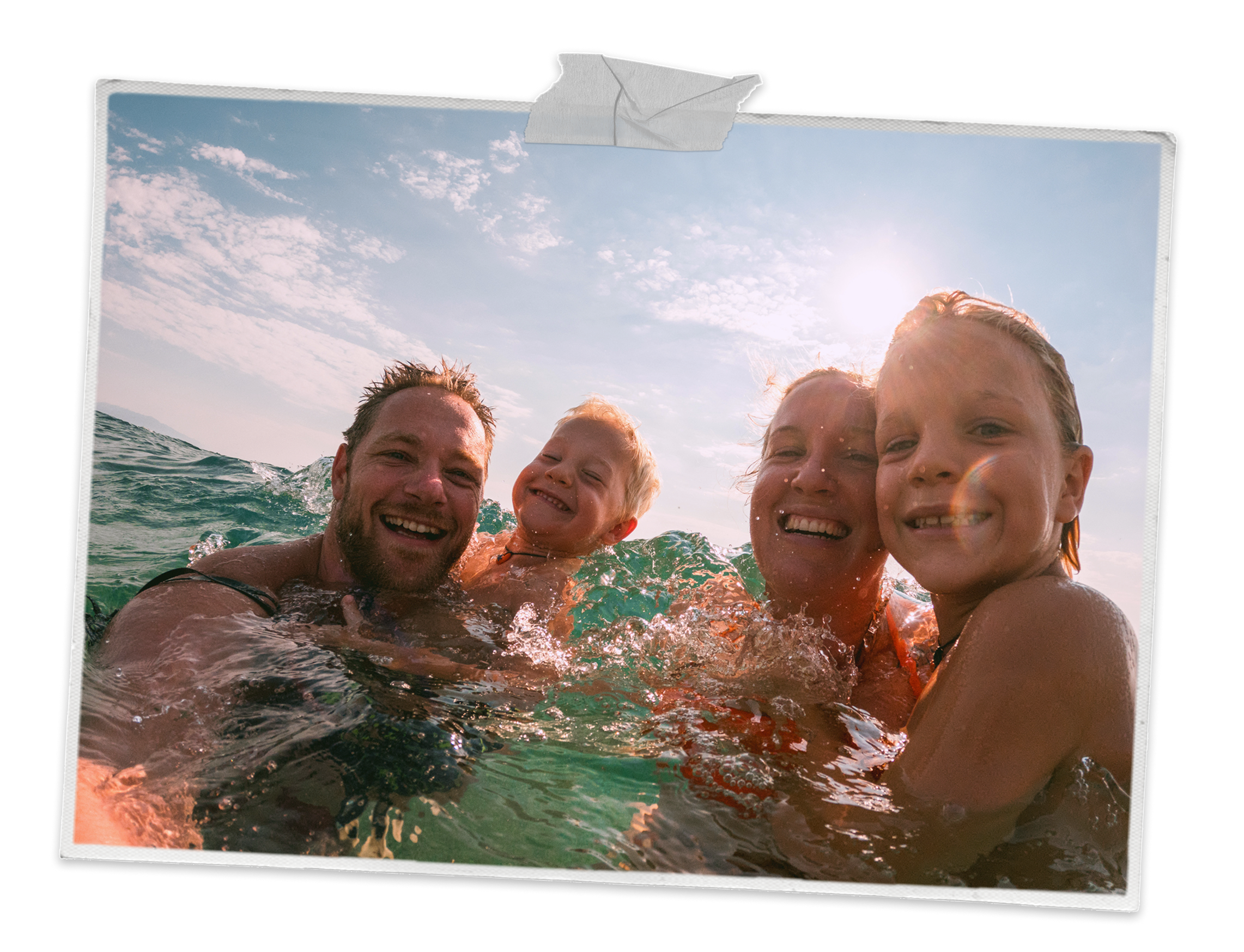 Two children and their parents swimming in the sea and smiling at the camera